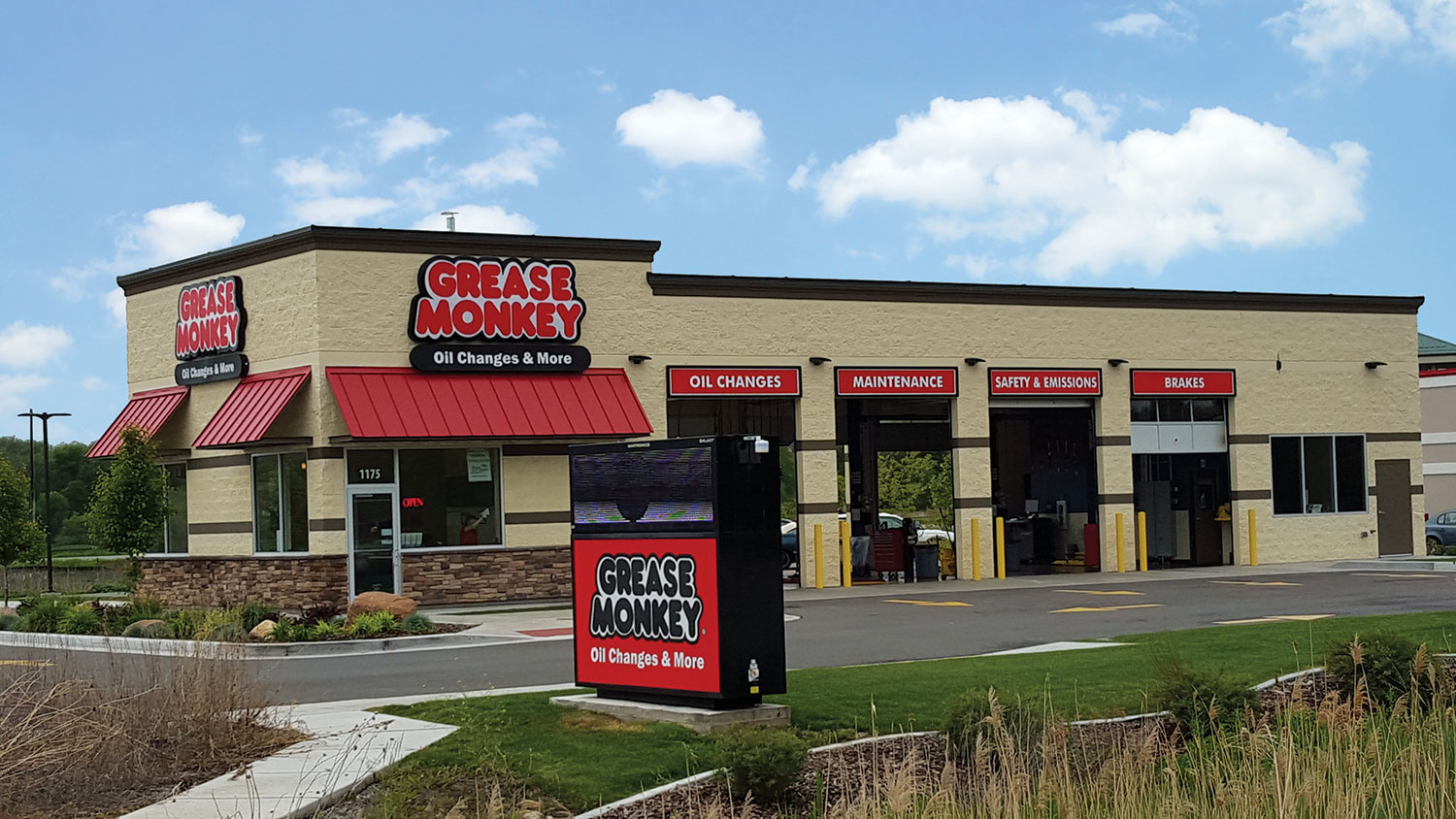 The outside of a Grease Monkey center with four service bays, shown on a sunny day.