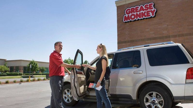Grease Monkey employee shakes hands with a customer outside the center.