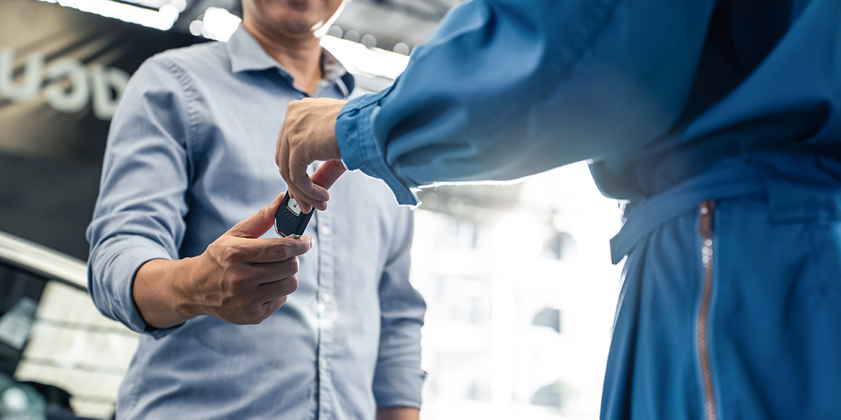 An auto tech at the Grease Monkey franchise hands a car key to a customer.